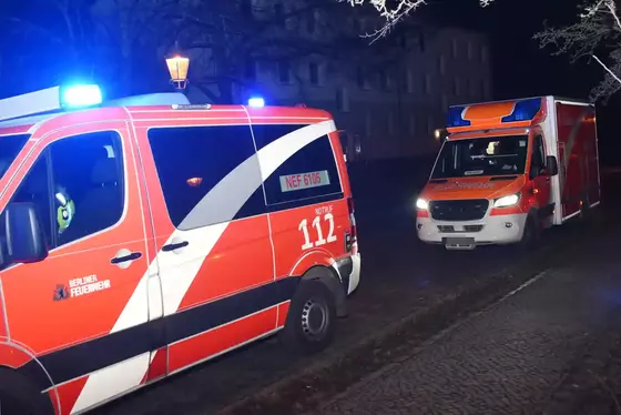 Zwei Rettungsfahrzeuge mit Blaulicht stehen nachts auf einer Straße vor dunklen Häusern.