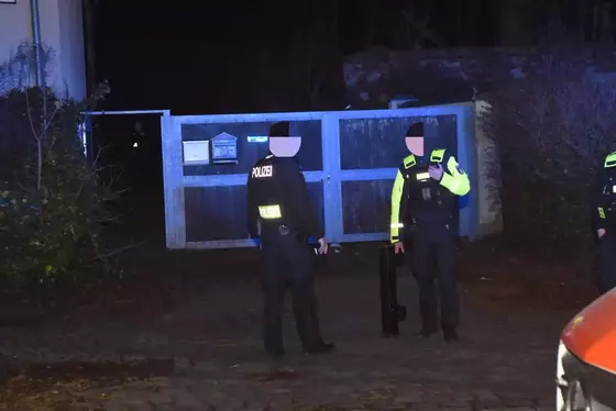 Zwei Polizisten in dunkler Kleidung vor einem geschlossenen Tor, einer hält eine Ramme in der Hand.