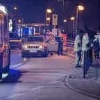 Jeep steht mit geöffneter Fahrertür an einer Haltestelle, mehrere Einsatzkräfte in reflektierender Kleidung warten an einem beschädigten Geländer bei Nacht