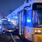 Straßenbahn und PKW stehen nachts eng nebeneinander an einer Unfallstelle mit eingeschaltetem Blaulicht und geöffneter Straßenbahntür