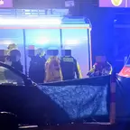 Nächtliche Unfallstelle mit mehreren Einsatzkräften von Polizei und Feuerwehr neben einem dunklen Fahrzeug und Einsatzfahrzeugen mit Blaulicht